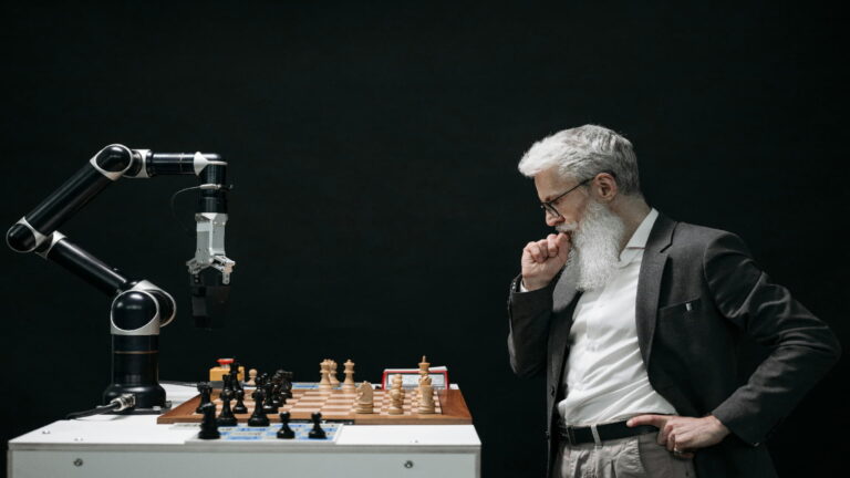 A man playing chess against a robotic arm in a dark setting.